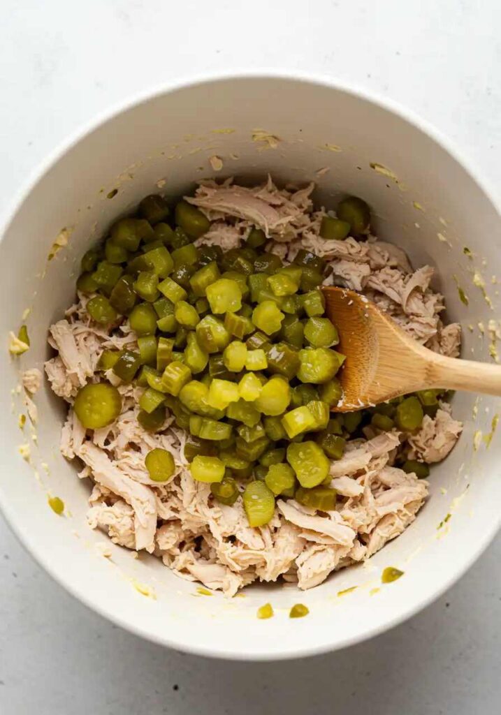 Mixing shredded chicken with pickles
